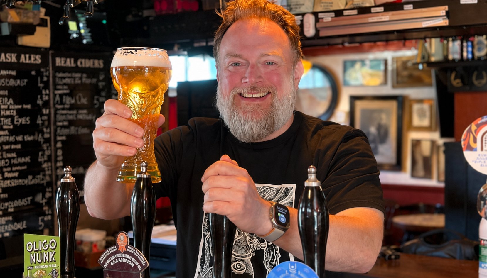 Bar owner proudly holding a BeerChampions trophy glass